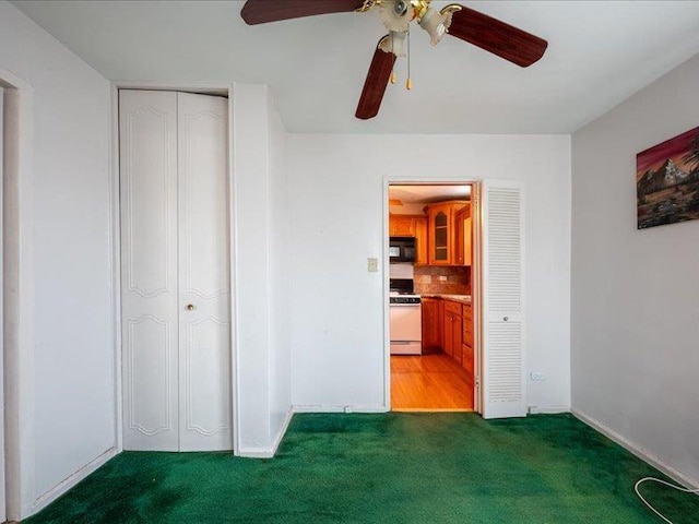 unfurnished bedroom featuring a closet, dark carpet, and ceiling fan