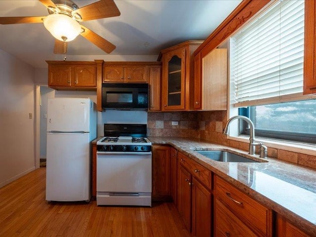 kitchen with white appliances, backsplash, sink, ceiling fan, and light stone counters