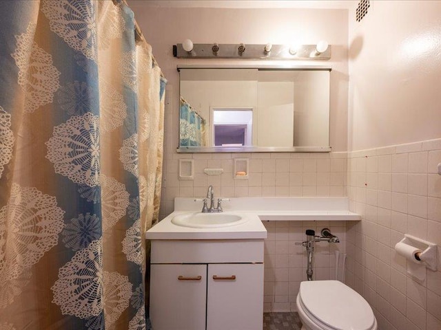 bathroom with vanity, tile walls, and toilet