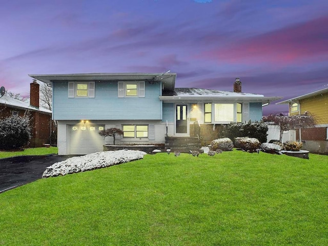 tri-level home featuring a lawn and a garage