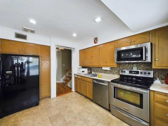 kitchen featuring decorative backsplash, sink, light tile patterned floors, and appliances with stainless steel finishes