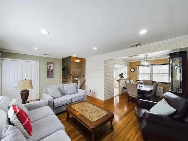 living room with dark hardwood / wood-style floors, crown molding, and brick wall