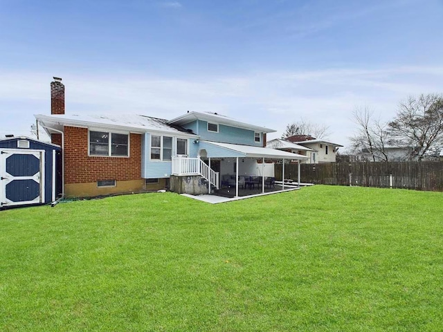 rear view of property with a yard, a patio, and a storage shed