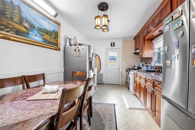 kitchen featuring radiator, sink, decorative light fixtures, stainless steel appliances, and a chandelier