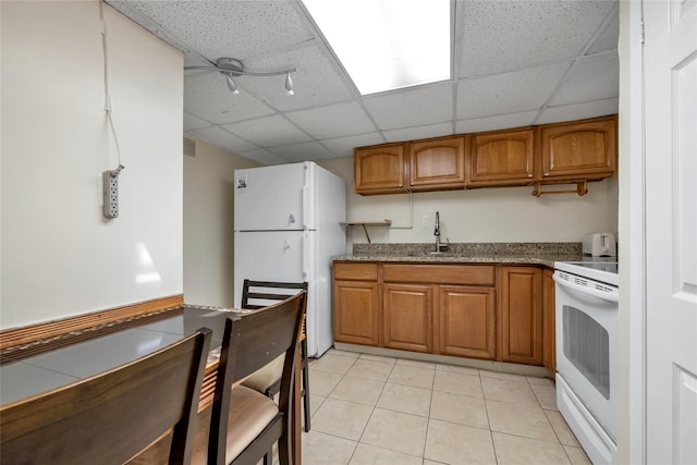 kitchen featuring a drop ceiling, sink, light tile patterned floors, white refrigerator, and range