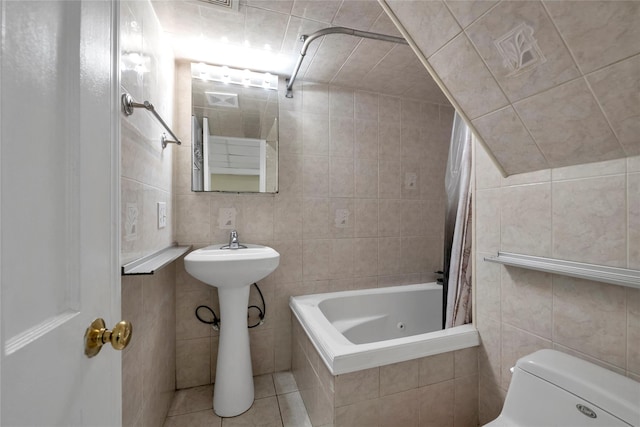 bathroom with tile patterned flooring, toilet, shower / bath combo with shower curtain, and tile walls