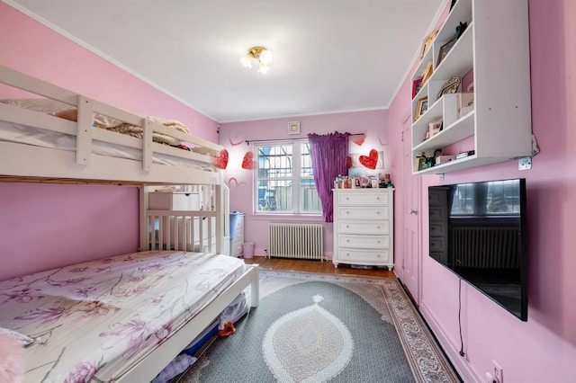 unfurnished bedroom featuring radiator heating unit, ornamental molding, and hardwood / wood-style flooring