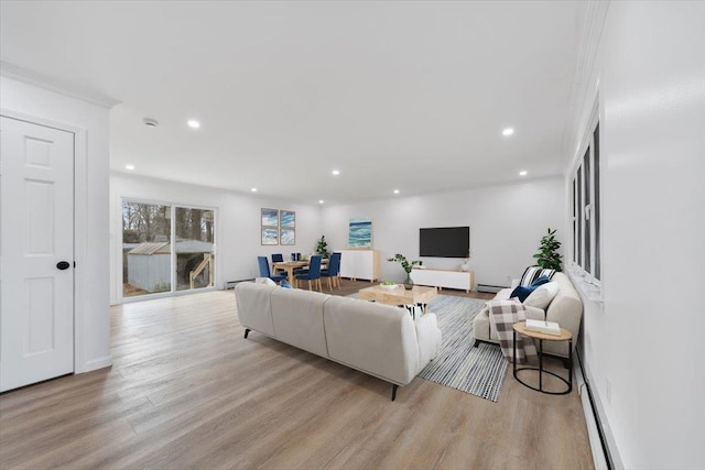 living room featuring light wood-type flooring, ornamental molding, and a baseboard heating unit