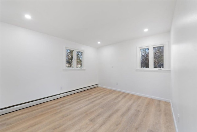 unfurnished room with baseboard heating and light wood-type flooring