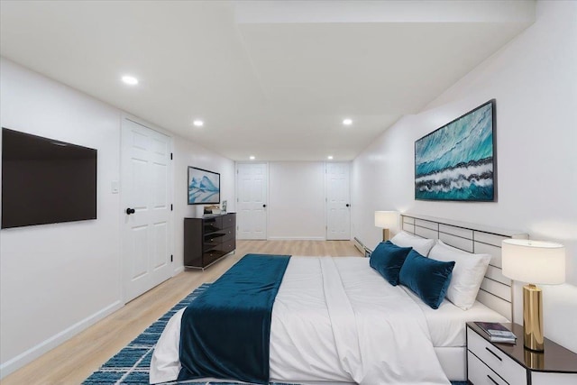 bedroom with light hardwood / wood-style floors and a baseboard radiator