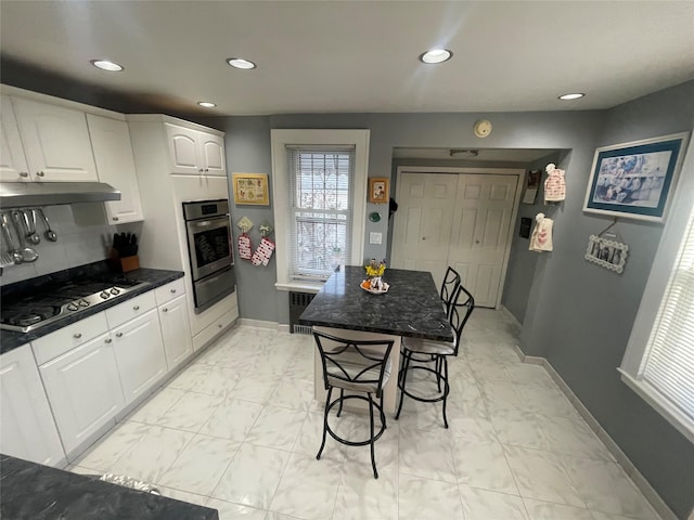 kitchen with appliances with stainless steel finishes, radiator heating unit, and white cabinets