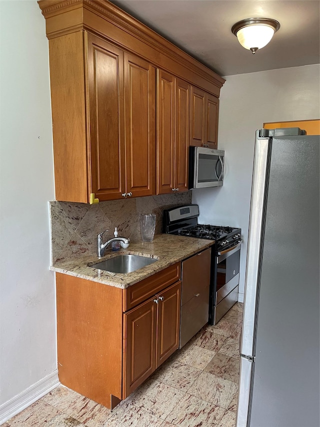 kitchen featuring appliances with stainless steel finishes, backsplash, light stone counters, and sink