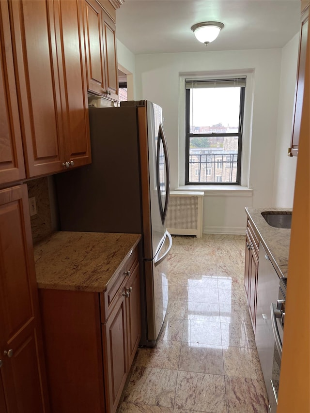 kitchen with stainless steel fridge, light stone countertops, and radiator heating unit