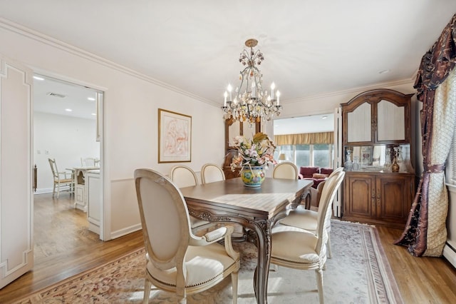 dining space featuring ornamental molding, light wood-type flooring, a baseboard heating unit, and an inviting chandelier