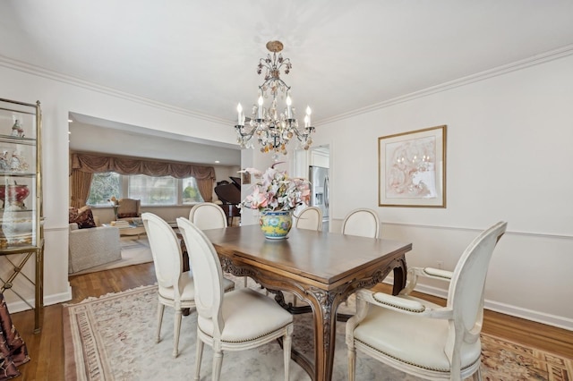 dining space with a chandelier, hardwood / wood-style flooring, and ornamental molding