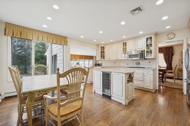 kitchen with a center island, wine cooler, light wood-type flooring, appliances with stainless steel finishes, and tasteful backsplash