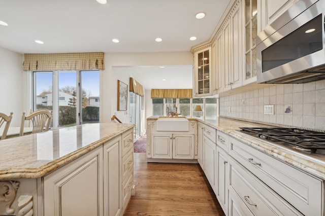 kitchen featuring light stone countertops, sink, stainless steel appliances, and light wood-type flooring