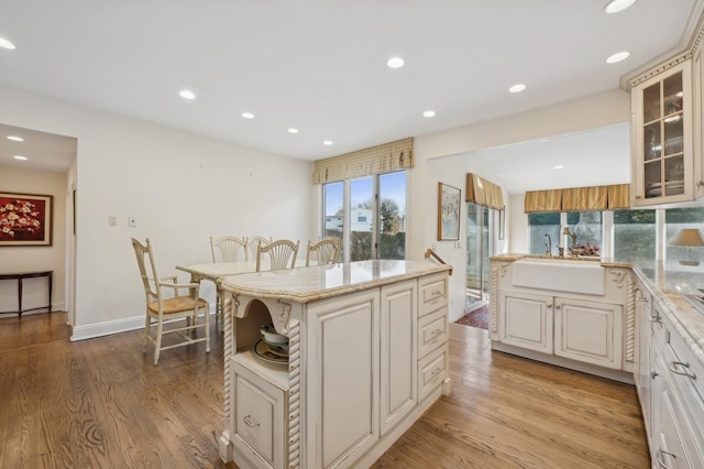 kitchen featuring light stone countertops, sink, a kitchen island, and light wood-type flooring