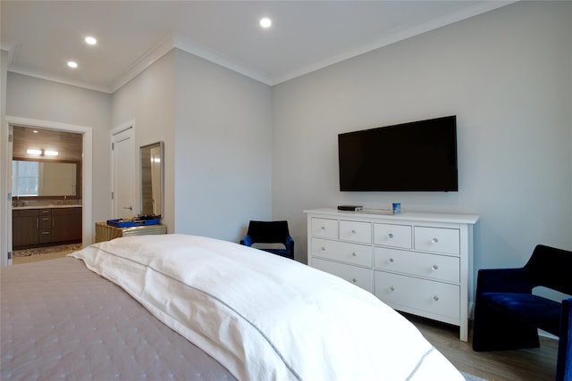 bedroom with hardwood / wood-style flooring, crown molding, and connected bathroom