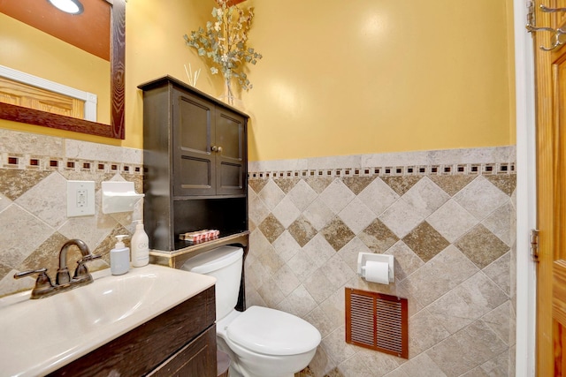 bathroom featuring vanity, tile walls, and toilet