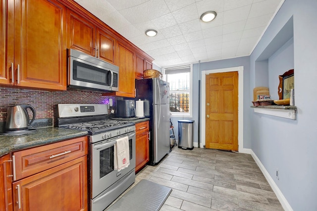 kitchen with backsplash, dark stone countertops, and appliances with stainless steel finishes