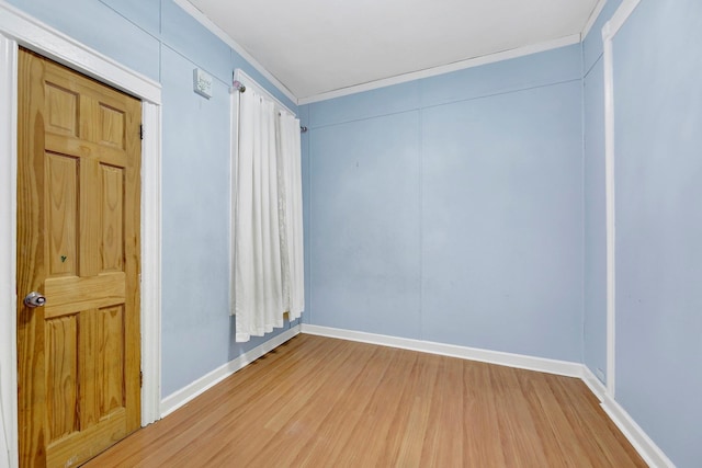 empty room with hardwood / wood-style flooring and crown molding