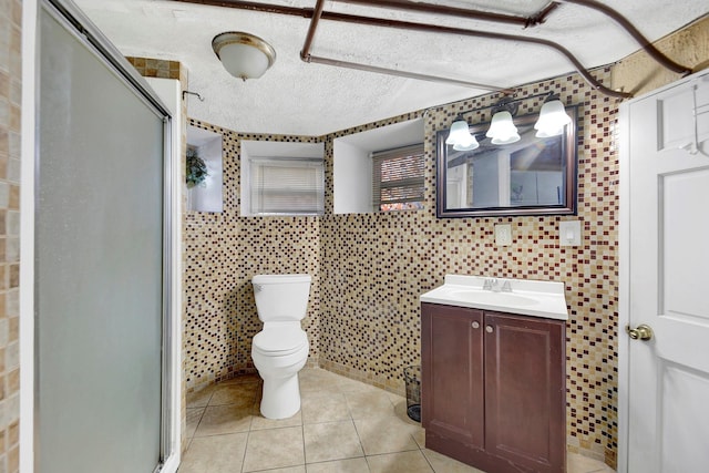 bathroom with tile patterned flooring, vanity, toilet, and a shower with door