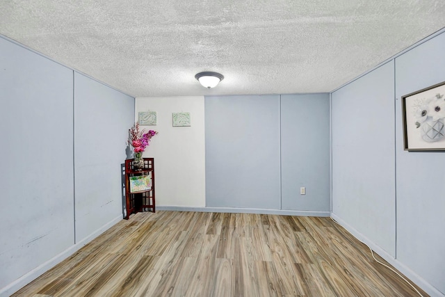 unfurnished room with a textured ceiling and light wood-type flooring