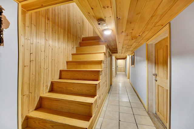 stairs featuring tile patterned flooring, wooden walls, and wood ceiling