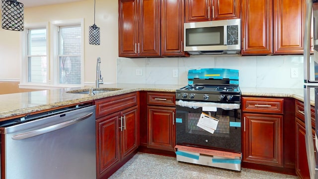 kitchen with sink, stainless steel appliances, tasteful backsplash, light stone counters, and decorative light fixtures