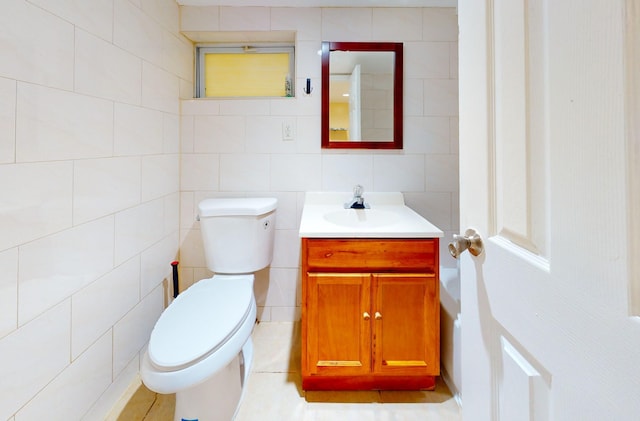 bathroom with vanity, toilet, and tile walls