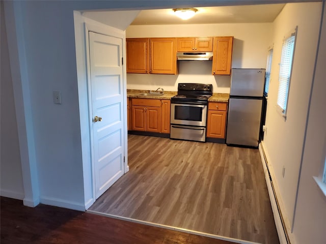 kitchen featuring stainless steel appliances, a baseboard heating unit, dark wood-type flooring, sink, and stone countertops