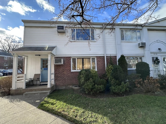 townhome / multi-family property with a wall unit AC and a front lawn