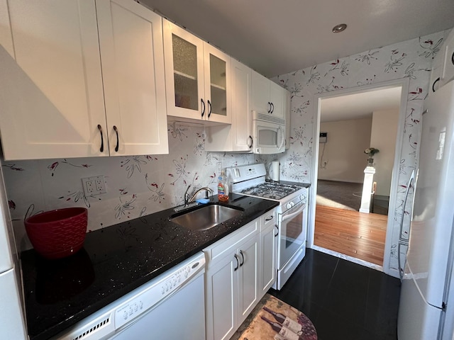 kitchen featuring dark stone countertops, white cabinetry, sink, and white appliances