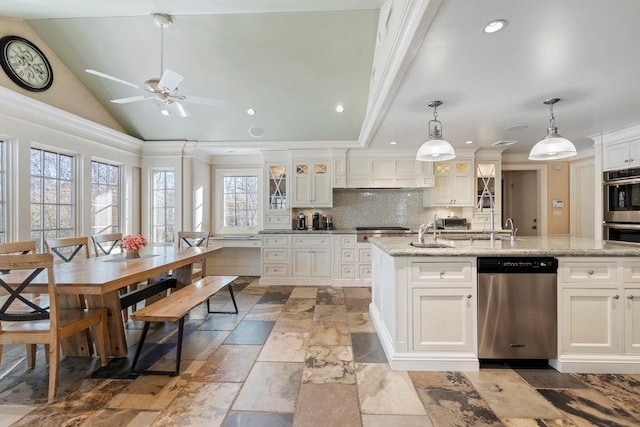 kitchen with pendant lighting, backsplash, a center island with sink, appliances with stainless steel finishes, and white cabinetry