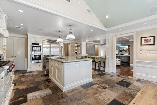 kitchen with sink, light stone counters, pendant lighting, a center island with sink, and appliances with stainless steel finishes