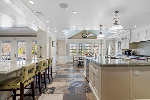 kitchen featuring a kitchen breakfast bar, light stone counters, dishwasher, and vaulted ceiling