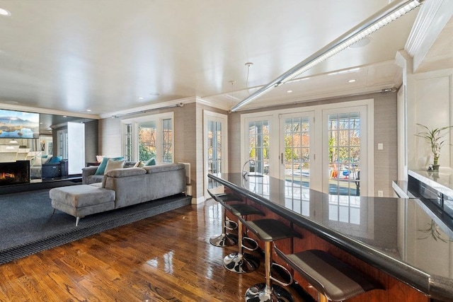 living room with crown molding, a wealth of natural light, and dark wood-type flooring