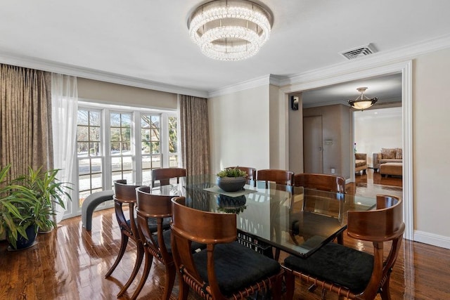 dining area with hardwood / wood-style flooring, crown molding, and a chandelier