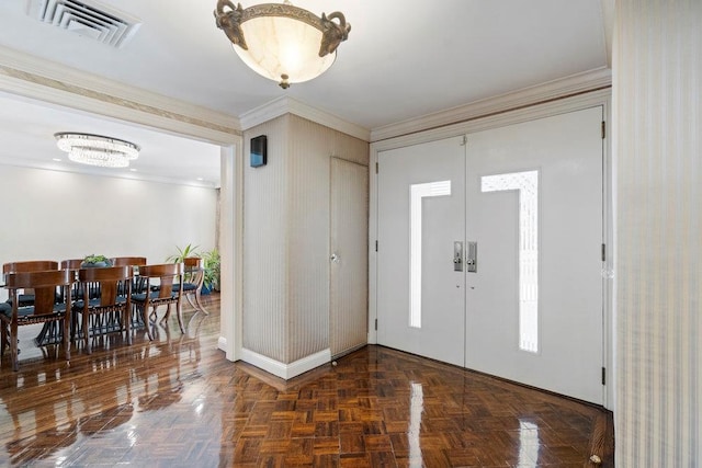 entrance foyer featuring dark parquet flooring, ornamental molding, and a chandelier