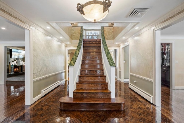 stairway featuring a premium fireplace, crown molding, parquet floors, and a baseboard heating unit