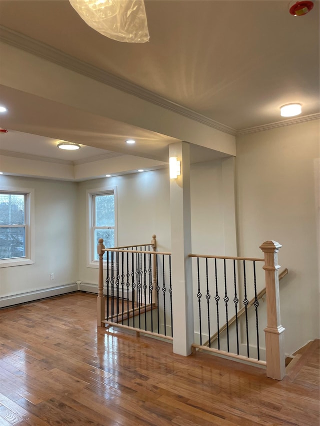 empty room with hardwood / wood-style flooring, a baseboard heating unit, and ornamental molding