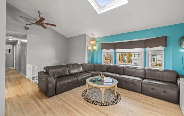 living area with a ceiling fan, vaulted ceiling with skylight, visible vents, and light wood-style flooring