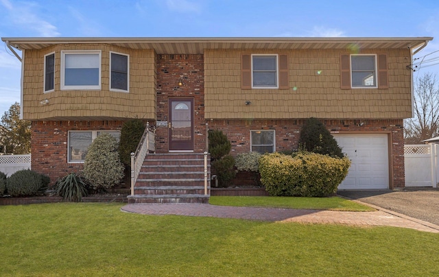 raised ranch with a garage, driveway, brick siding, and a front lawn