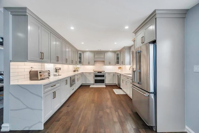 kitchen featuring dark wood-type flooring, sink, light stone countertops, tasteful backsplash, and stainless steel appliances