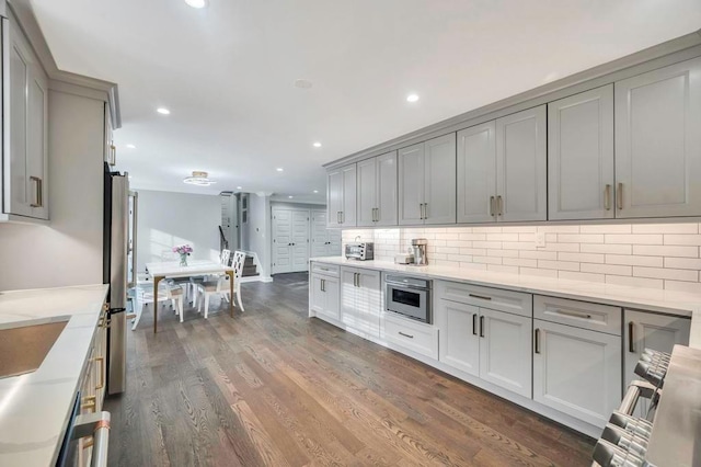 kitchen featuring backsplash, dark hardwood / wood-style floors, stainless steel refrigerator, and gray cabinetry