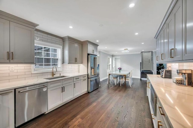 kitchen with sink, gray cabinets, light stone counters, dark hardwood / wood-style flooring, and stainless steel appliances