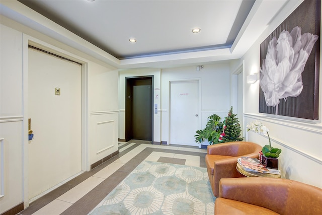 hallway with a raised ceiling and light tile patterned flooring