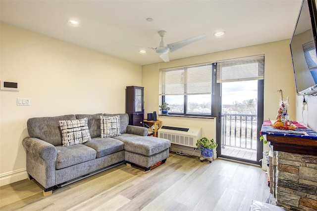 living room with light wood-type flooring, a wall unit AC, and ceiling fan