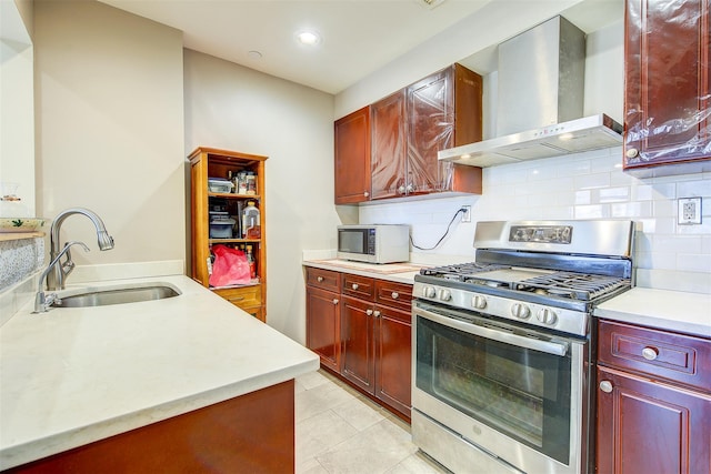 kitchen featuring sink, tasteful backsplash, wall chimney exhaust hood, and stainless steel range with gas stovetop